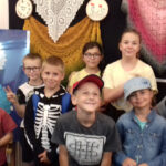 Dzieci oglądają wystawę haftu i koronki (serwety, chusty).