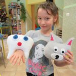Dziewczynka trzyma w rękach swoje maskotki – ząbek i psa.