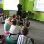 Dzieci oglądają prezentację w sali edukacyjnej “Ognik” PSP