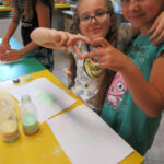 Dziewczynki podczas kolorowania soli układają palce w kształt serca