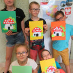 Dzieci trzymają obrazki z muchomorkami – wycinanka z papieru