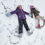 Dziewczynki robią „aniołki” na śniegu