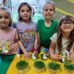Cztery dziewczynki prezentują efekty swojej pracy – wyhodowaną rzeżuchę i stroiki